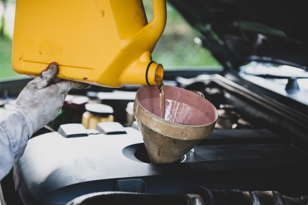 Fresh engine oil being poured during a routine car service